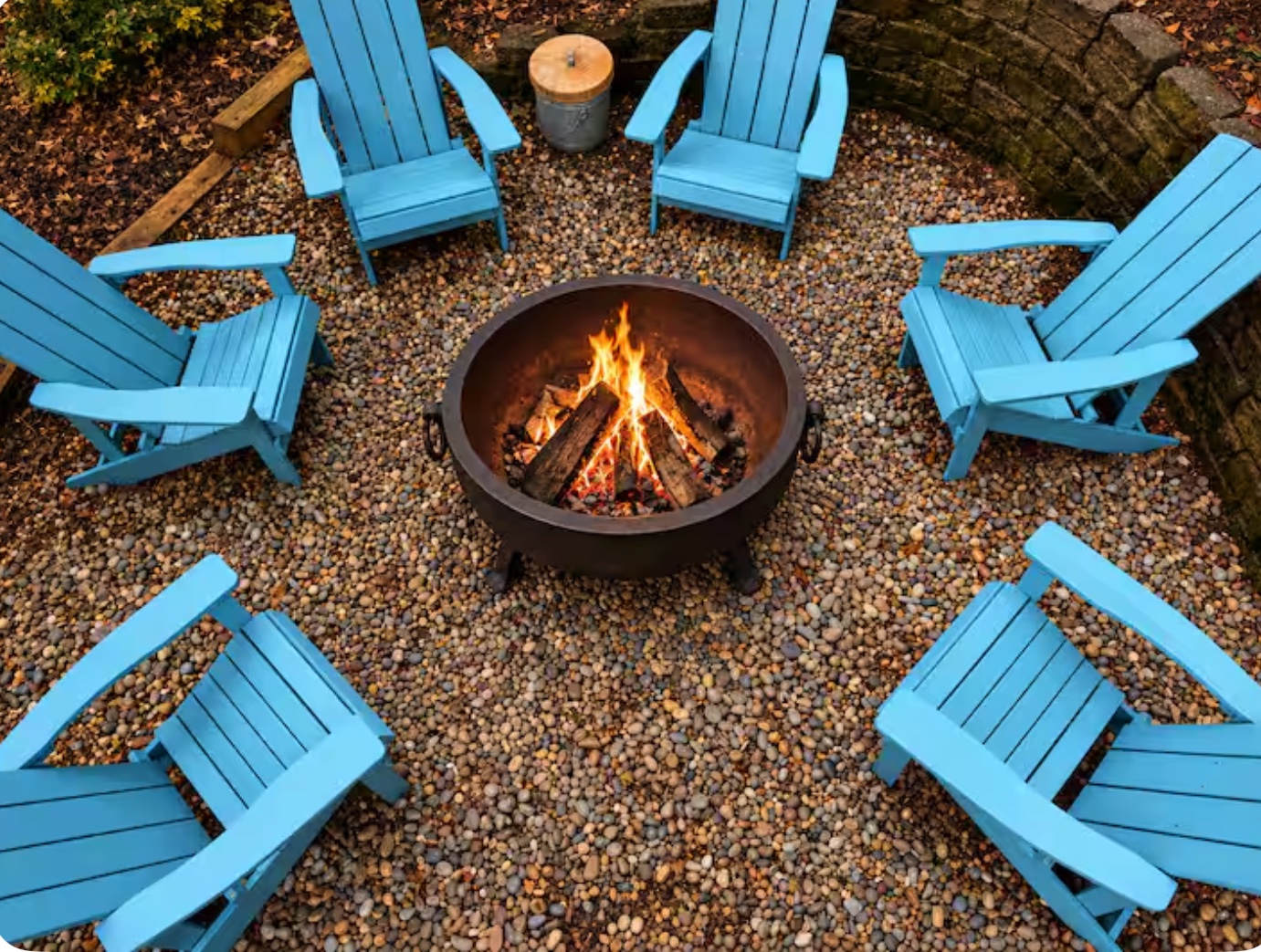 Fire pit surrounded by blue Adirondack chairs